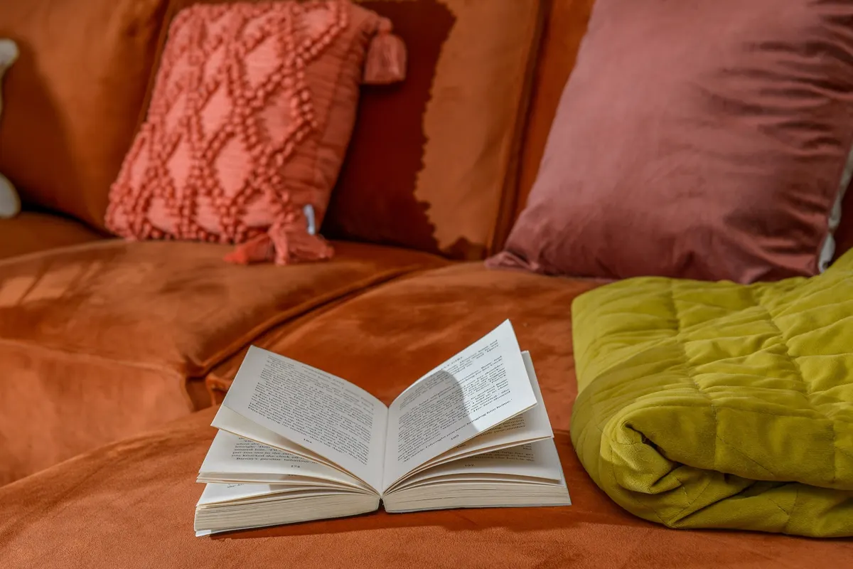 Open book and cushions on the living room sofa