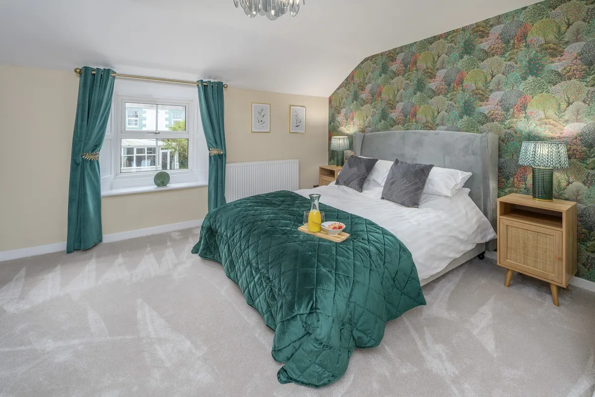 King-size bedroom with green bedding and patterned wallpaper